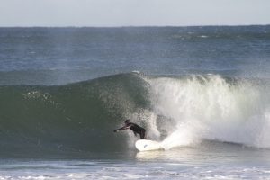 Image of a man surfing a big wave expressing joy.